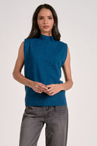 Woman wearing a blue sleeveless sweater against a white background
