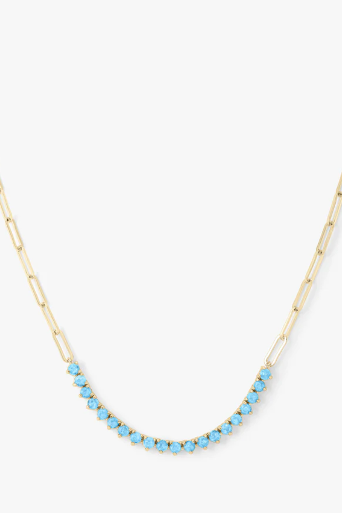 Necklace with blue beads on a gold chain against a white background