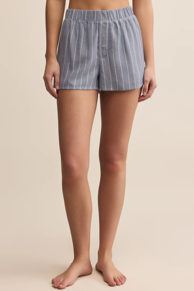 Person wearing blue striped shorts on a beige background