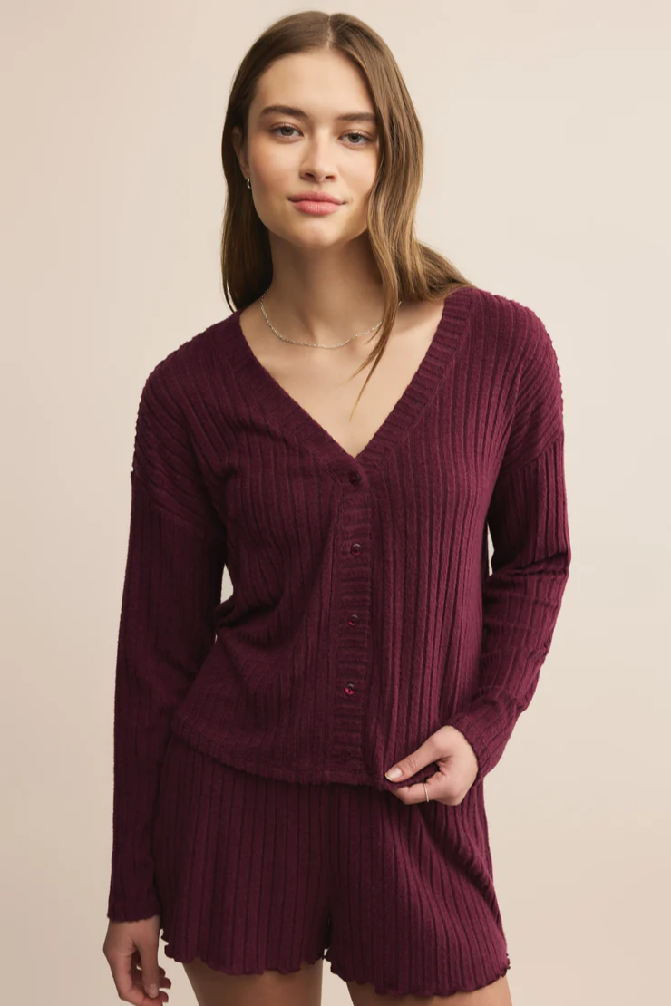 Woman wearing a ribbed burgundy sweater and shorts set on a beige background