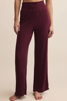 Maroon ribbed pants worn by a person on a beige background