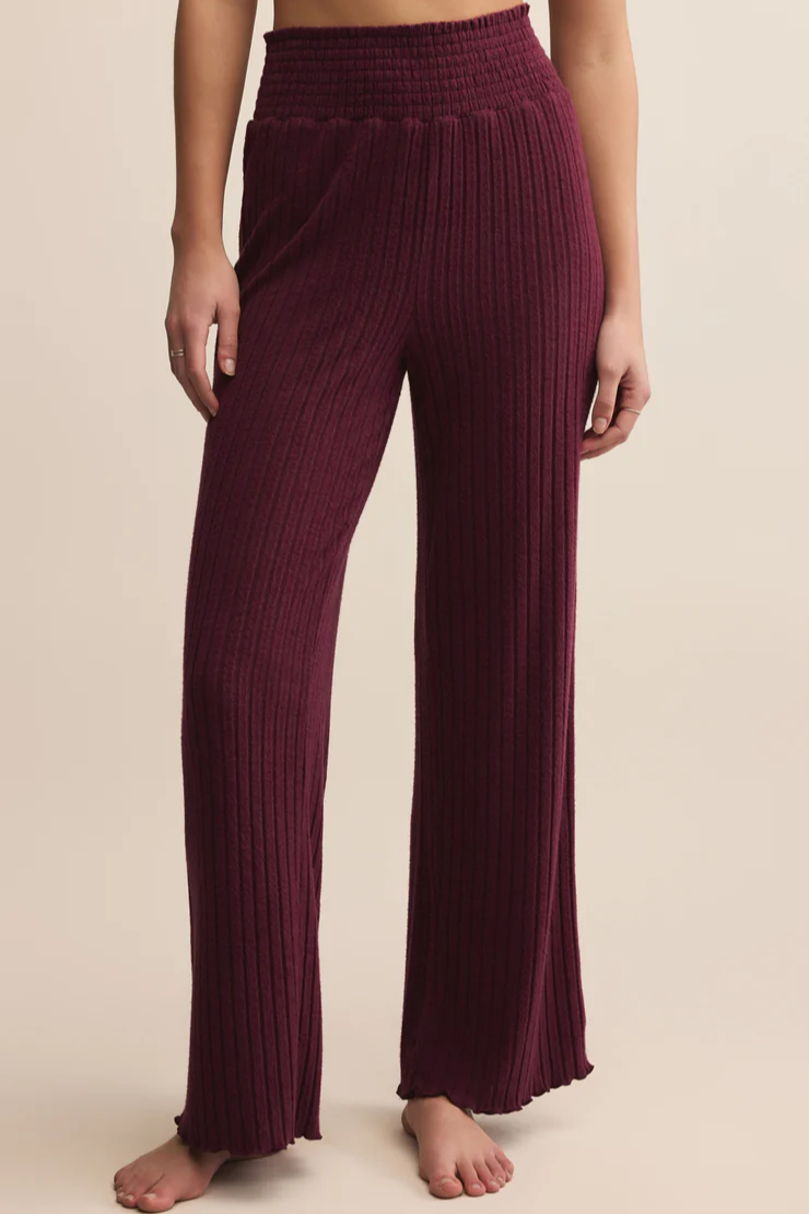 Maroon ribbed pants worn by a person on a beige background