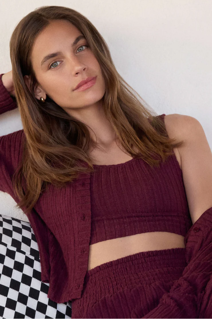 Woman wearing a maroon outfit against a checkered floor and white wall background
