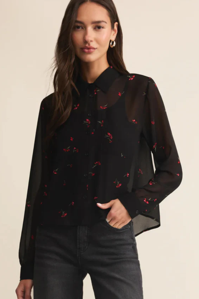 Woman wearing a black blouse with red floral patterns on a beige background