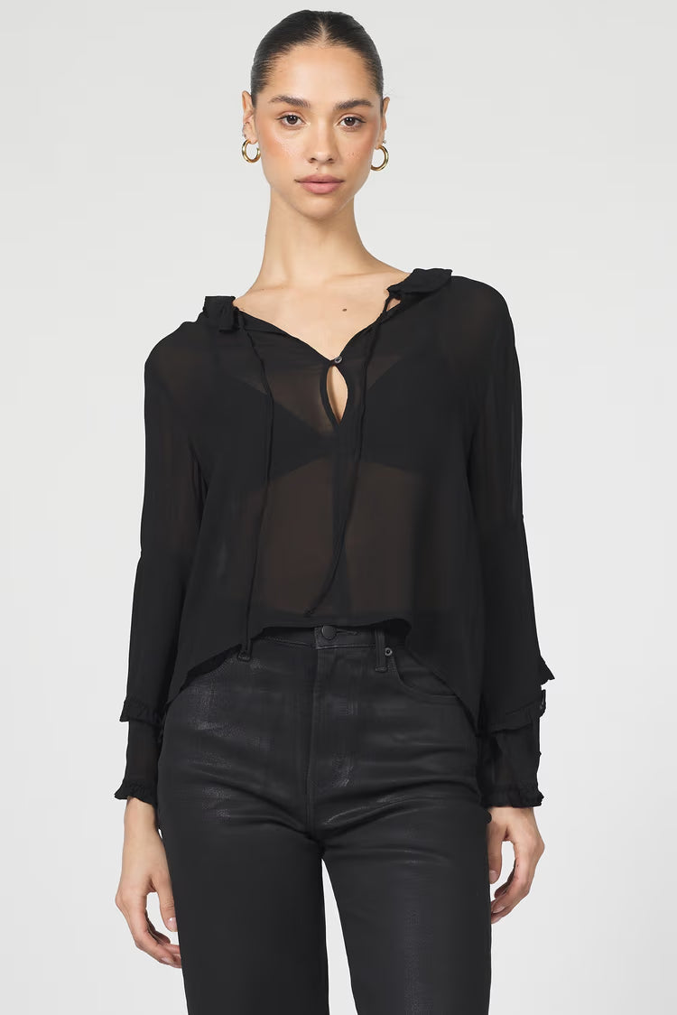 Woman wearing a black sheer top and black pants on a white background