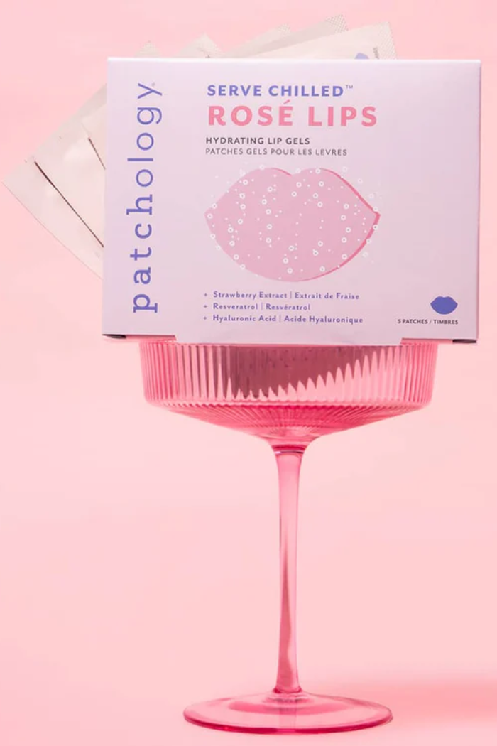 Patchology Rose Lips packaging on a pink background with a pink glass.