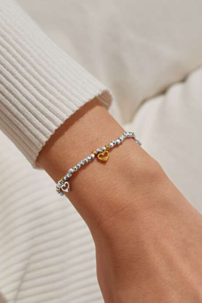 Close-up of a wrist wearing a bracelet with heart charms on a light background