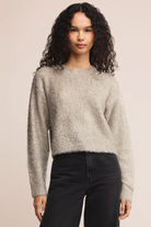 Woman wearing a textured sweater and black pants against a beige background