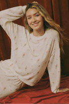 Woman wearing a white long-sleeve top with small patterns, sitting on a red surface.