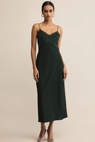 Woman wearing a dark green slip dress against a beige background