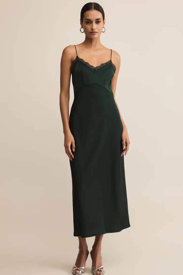 Woman wearing a dark green slip dress against a beige background