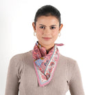 Pink floral Vismaya Florentine Bandana tied loosely around woman's neck over beige sweater
