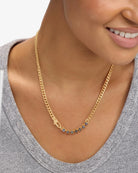 Woman wearing gold curb chain necklace with blue-gray labradorite stones over gray sweater